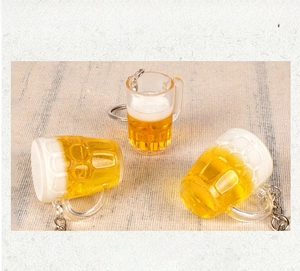 Detailansicht von drei Mini-Bierkrug-Schlüsselanhängern mit Schaum auf strukturiertem Stoff