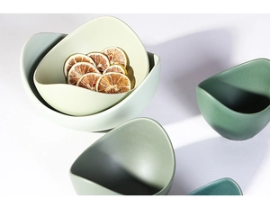 Macro view of matte ceramic bowls in Morandi green and cream with unique lotus petal shapes