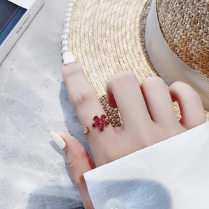 Close-up of elegant rose gold open ring with red crystal flower petals worn on hand