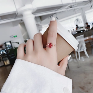 Close-up of red crystal flower ring with adjustable band worn while holding a coffee cup