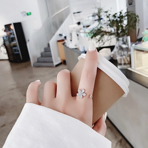 Close-up of rose gold adjustable flower ring with blue petals on model's finger
