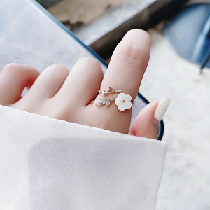 Elegant gold flower ring with white petals and shimmering crystals on female hand