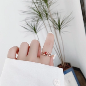 Close-up of stacked rose gold rings with red crystal flower and zircon stones on finger
