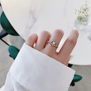 Detailed view of rose gold floral ring with pink heart stone and fine zircon on a finger