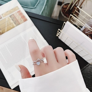 Detailed view of silver flower and blue heart crystal rings worn on finger
