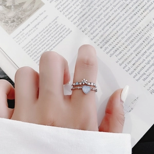 Detail of stacked silver flower rings with blue heart crystal on a female hand