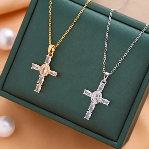 Cross pendant necklaces in gold and silver with zircon inlays on green jewelry box
