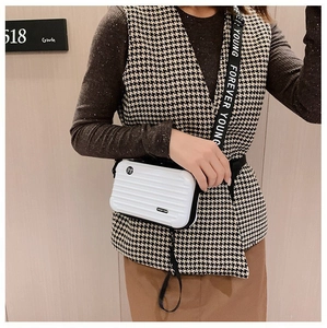 White hard shell mini crossbody bag with travel suitcase texture and lettered strap