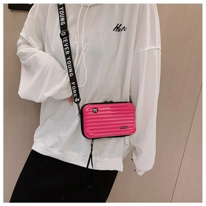 Detail of pink mini suitcase bag featuring ribbed hardshell texture and logo strap