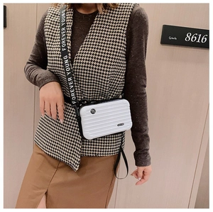 Close-up of white mini suitcase bag with hardshell vertical stripes and wide logo strap