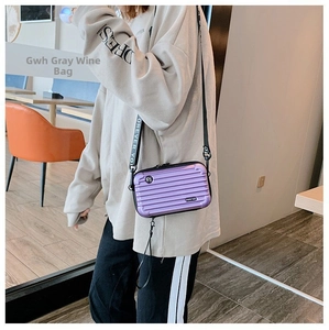 Detail of a shiny purple mini hardshell suitcase crossbody bag with Forever Young strap
