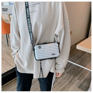 Detail of silver hardshell mini suitcase bag with Forever Young strap on a casual model