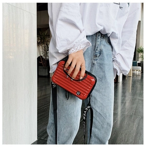 Red hardshell mini suitcase bag with Forever Young strap worn by a model