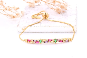 Detail van gouden box-ketting armband met kleurrijke rechthoekige kristallen en marmeren basis