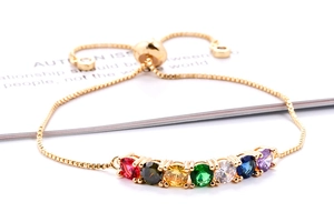 Detail van de gouden armband met zeven gekleurde zirkoonstenen en verstelbare treksluiting