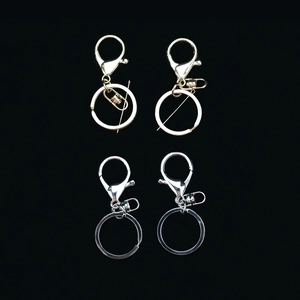 Polished silver and gold lobster clasp keychains with metal rings on a black background