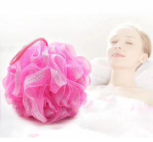 Pink bath sponge ball with silver glitter silk and hanging rope shown in a bathroom setting