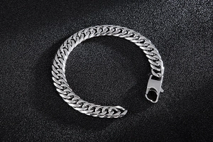 Close-up of a polished silver stainless steel Cuban link bracelet with a lobster clasp