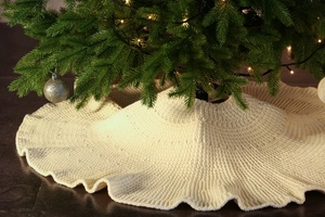 Close-up of cream knitted Christmas tree skirt with wavy edges and soft crochet texture