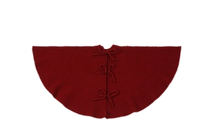Close-up of deep red knitted Christmas tree skirt with decorative bow tie closures