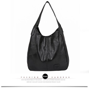 Close-up of black leather tote bag with pebble texture and thick shoulder strap