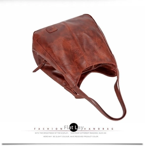 Detailed view of brown retro textured leather tote bag with branded label and handles