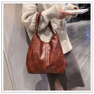 Close-up of vintage brown leather tote bag with patchwork texture and square logo patch