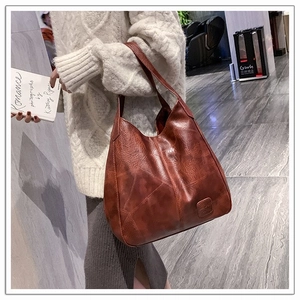 Brown leather tote bag featuring contrast stitching and large capacity shown on model