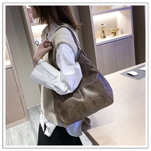Close-up of a large dark brown tote bag with leather texture and shoulder strap