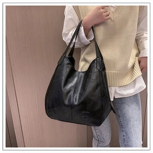 Detail showing crocodile texture on large black faux leather tote bag on model shoulder