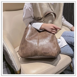 Detail of soft brown leather tote bag showing vintage texture and diagonal stitching