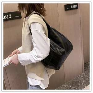 Close-up of a black glossy soft leather shoulder bag with a natural grain texture