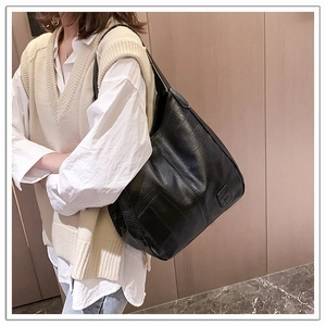 Close-up of black crocodile pattern shoulder bag with polished square decorative patch