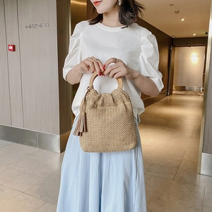 Fashionable straw handbag with round wooden handles and tassel detail for summer vacations