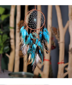 Close-up of tree of life dreamcatcher with turquoise bead and dangling feathers