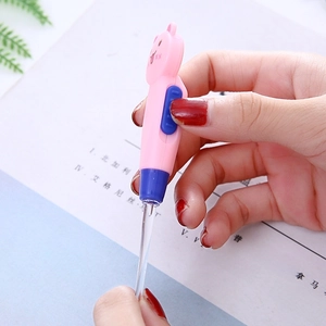 Pink bear-shaped glowing ear pick with LED light and clear plastic tip held by hand