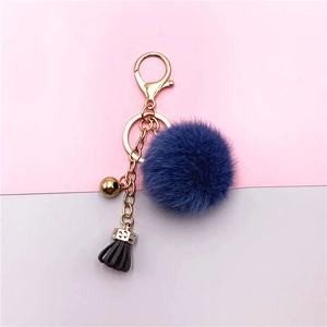 Detailed shot of a blue faux fur pompom keychain with golden lobster clasp and tassel