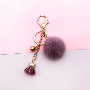 Detail of purple fluffy fur pompom keychain with matching leather tassel and golden bell