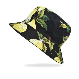 Close-up of black bucket hat featuring vibrant lemon and green leaf prints on cotton fabric