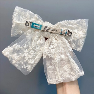 Detail of white double-layer lace bow hair clip with floral embroidery and silver metal barrette