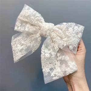 Close-up of white lace embroidery mesh bow hair clip with delicate floral patterns