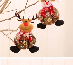 Close-up of reindeer and snowman fabric ornaments with bells hanging on a branch