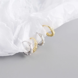 Dettaglio di orecchini geometrici a cerchio stile bambù con zirconi in oro e argento
