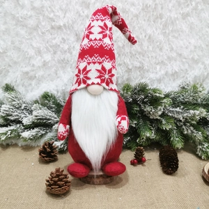 Christmas gnome doll with red knitted hat and white beard on a winter forest base