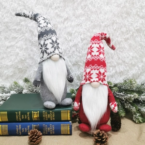 Close-up of knit Christmas gnomes with snowflake patterns on vintage books with pine cones