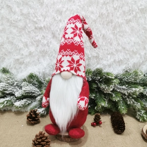 Close-up of a festive red and white knitted Christmas gnome on a stable wooden base