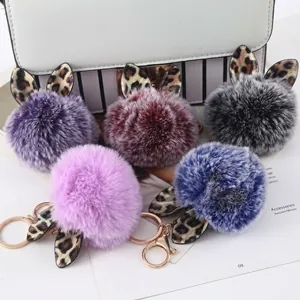 Detailansicht bunter Kunstpelz-Schlüsselanhänger mit Leopardenohren auf weißer Handtasche