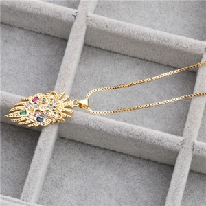 Golden lion head pendant necklace with multi-colored zircons on grey velvet tray