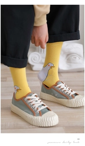 Nahaufnahme von gelben Entensocken aus Baumwolle mit grünen Canvas-Sneakern kombiniert