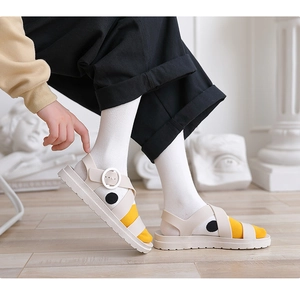 Nahaufnahme cremefarbener Sandalen mit gepunkteten Socken auf Holzfußboden